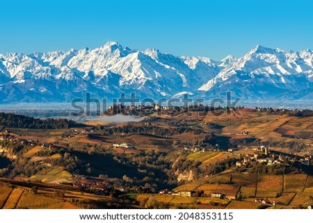 View from above of autumnal hills and snowy mountains on background under blue sky in Piedmont, Northern Italy. Royalty-Free Stock Photo #2048353115