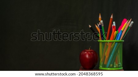 Back to school background with books with school supplies and apples set on wooden floor. with a blackboard background