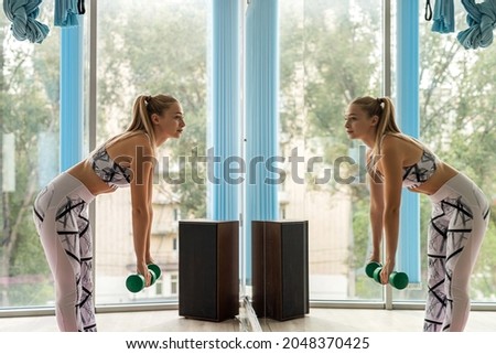 pretty blonde girl doing exercise with light dumbbells in the fitness studio, sport as lifestyle