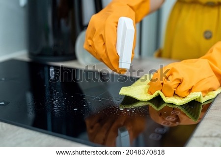caucasian housewife cleans with spray and protective gloves the kitchen at her home