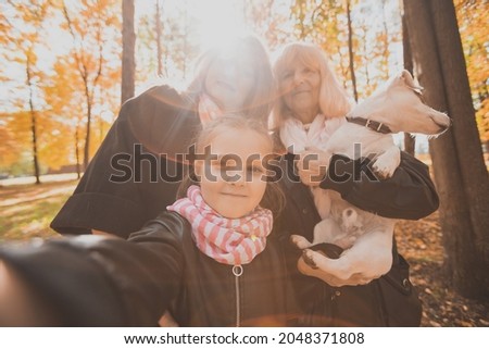 Three generations of women and dog feel fun look at camera posing for self-portrait picture together, funny excited child, mom and grandmother have fun enjoy weekend take selfie on gadget in autumn
