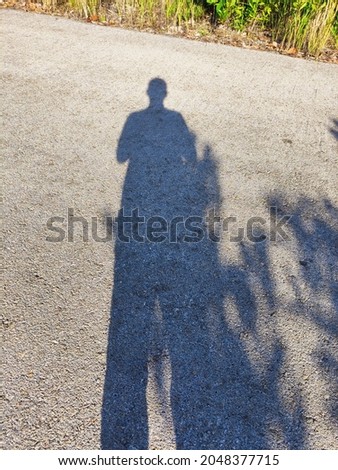 A shadow of a man on a roadside in the morning. 
