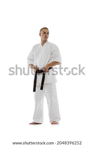 Portrait of professional karateka in kimono with black belth isolated over white background. Karate, judo, taekwondo sport. Maintaining strength. Concept of martial art, combat sport, energy, fit, ad Royalty-Free Stock Photo #2048396252