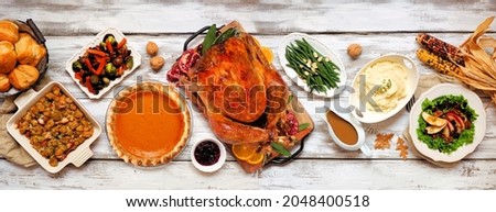 Traditional Thanksgiving turkey dinner. Above view table scene on a rustic white wood banner background. Turkey, mashed potatoes, stuffing, pumpkin pie and sides.