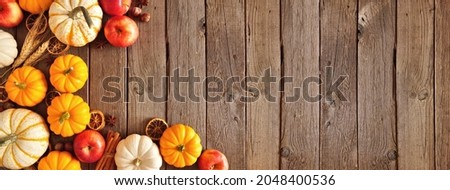 Fall corner border of pumpkins, apples and spices. Top view on a rustic dark wood background with copy space.