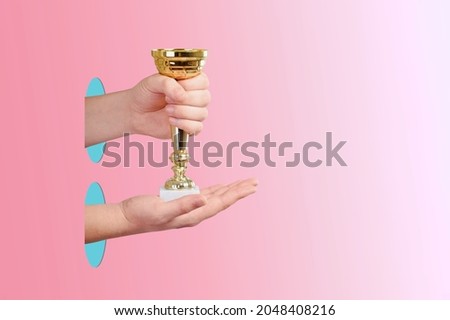 Hand of human holding gold winner cup, award and victory concept.