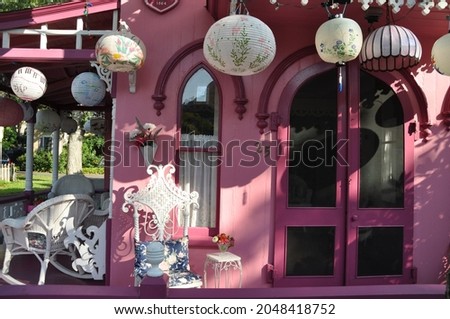 Chinese and Japanese lanterns hanging on a pink porch in Wesleyan Grove on Martha's Vineyard, MA. Taken at Marsh's Vineyard Camp Meeting Association.  Royalty-Free Stock Photo #2048418752