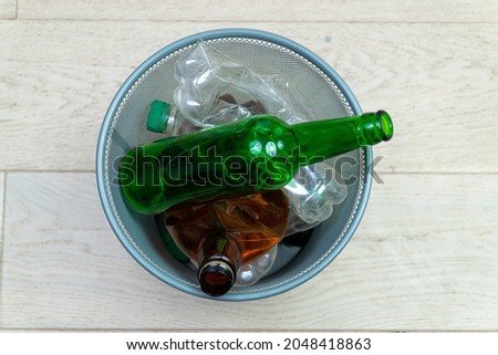 Different plastic and glass bottles in the office trash can. Ecology and recycling of waste from various raw materials