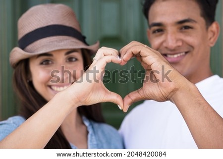 Portrait of happy couple making heart shape sign with hands. Happy adult couple falling in love making heart shape symbol with hands. Romantic loving couple making heart sign with hands