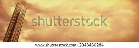 Wooden thermometer showing high temperature over 44 degrees Celsius on hell hot day. Orange sky with clouds background. Panorama. Concept of heat wave , warm weather, global warming, climate change. Royalty-Free Stock Photo #2048436284