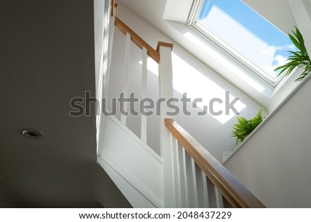 Abstract view of a newly installed loft conversion seen from the ground floor, looking at the staircase. A skylight window is seen on a sunny day. Royalty-Free Stock Photo #2048437229