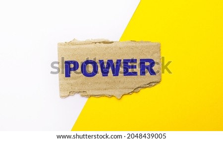 On a white and yellow background, brown torn cardboard with the text POWER