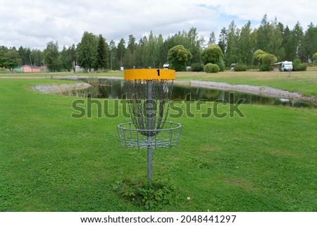 Discgolf park located in finland. Professional discgolf basket on the course. Target for throwing discs. Basket with lots of chains for best catching properties. Discgolf course by the lake