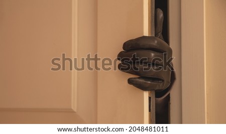 Housebreaking, burglary concept. Gloved hand opening the entrance door, burglar entering illegally the house Royalty-Free Stock Photo #2048481011