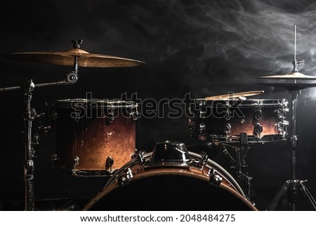 Part of a drum kit against a black background, percussion instrument, snare drum, bass drum, hi-hat on stage under the spotlights. Royalty-Free Stock Photo #2048484275