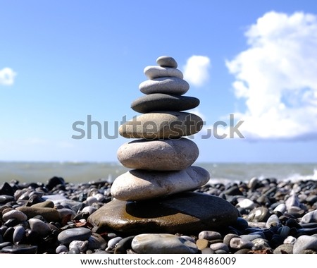 Pyramid, balance of stones on the seashore against the blue sky. 