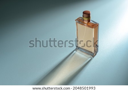 Perfume bottle with automatic dispenser on a blue background and a beautiful light effect. Perfume, cosmetic branding concept. Eau de parfum, luxury beauty brand