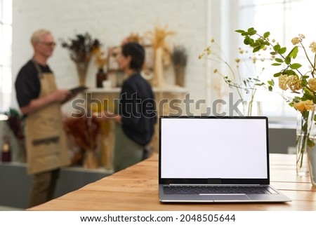 Background image of opened laptop with blank white screen in flower shop small business interior, copy space