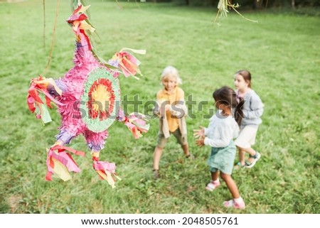 Background image of pink pinata at Birthday party with diverse group of kids playing outdoors, copy space