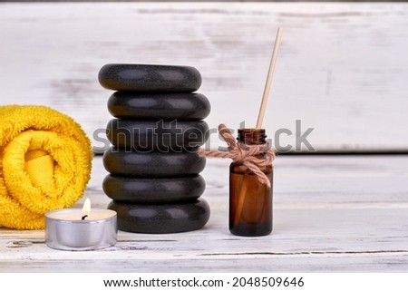 Stack of stones with candle and rolled terry towel.