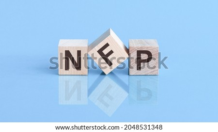 NFP word is made of wooden cubes lying on the blue table, business concept. NFP short for Non Farm Payroll