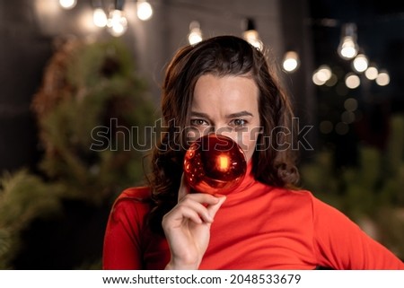 Christmas interior with new year tree before celebration. Woman hiding her face behind Christmas toy. Studio for photo session. New year concept