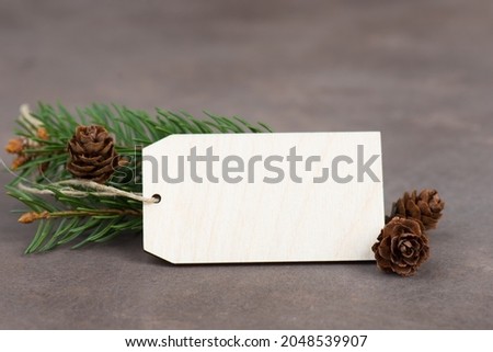 Empty sign with christmas decoration, branch of fir and cones, textured brown background