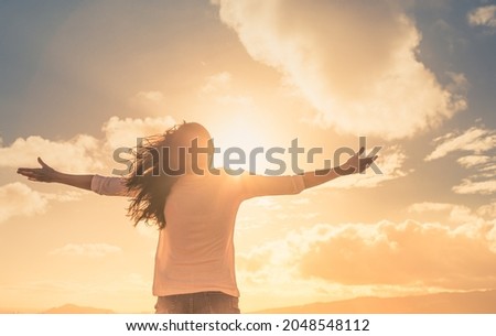 Young woman with with arms outstretched up to the beautiful sunrise sky. Freedom, feeling inspired and seeing the light concept.  Royalty-Free Stock Photo #2048548112