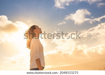 Attractive young woman looking up to the beautiful sky with feelings of hope and happiness.  Royalty-Free Stock Photo #2048553275
