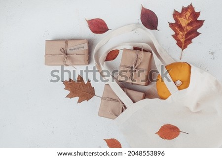 Autumn pumpkin, gift, fallen leaves in shopping eco-friendly bag isolated on white background, top view. Autumn composition. Thanksgiving, fall concept.