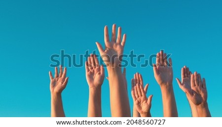 People rasing hands on blue sky background. Voting, democracy or volunteering concept Royalty-Free Stock Photo #2048560727