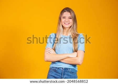 Beautiful blonde woman isolated on yellow background. Beautiful caucasian woman wearing casual  tshirt happy face smiling with crossed arms looking at the camera. positive person.