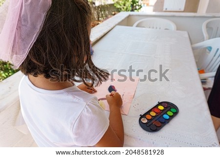 Girl painting with watercolor on table at home balcony, caucasian girl watercolor painting on holiday.