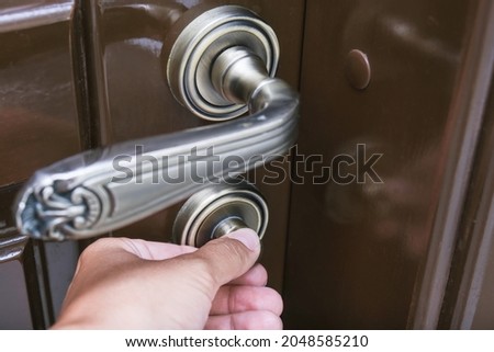 Hand locking a brown door using a knob for safety and privacy, home security concept.