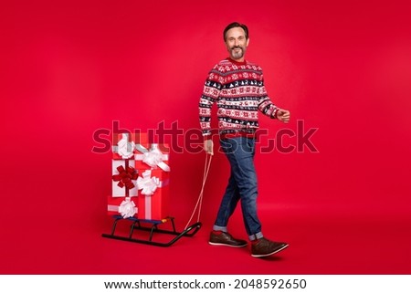Full length body size photo man walking with sledges present boxes pile on new year isolated bright red color background
