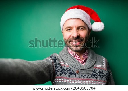 Personal perspective of a handsome man taking a selfie with a santa hat against a green background
