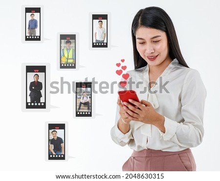 Young happy businesswoman using smartphone finding in online dating app and looking for profile photos of young guys. Single business woman looking at handsome men images on love match website.