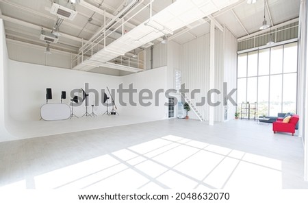 Empty wide and tall new  clean industrial architecture design for professional photography indoor studio classroom workshop with tall glass windows with flash strobe tripod stand reflector equipment.