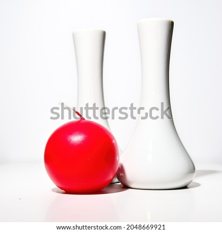 Red round candle on a background of white vases.