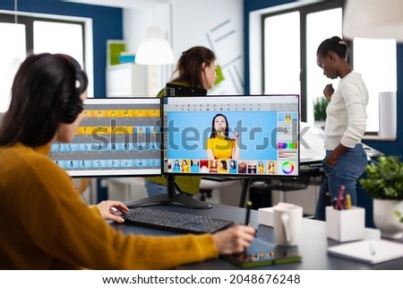 Caucasian photographer woman sitting at desk listening music using PC in studio agency office. Designer content creator doing portrait retouching using post production software