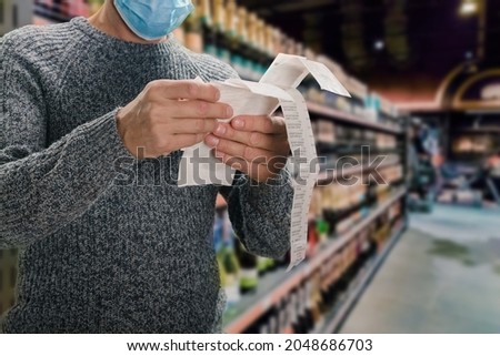 Male customer doing grocery shopping at supermarket and feeling confused by bill Royalty-Free Stock Photo #2048686703