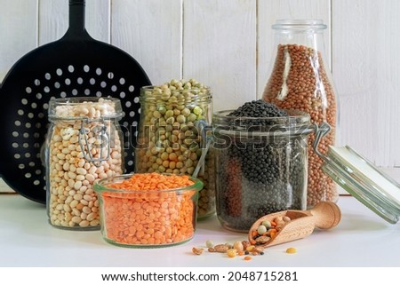 Assortment of colorful legumes in jars and glasses on a light kitchen table Royalty-Free Stock Photo #2048715281