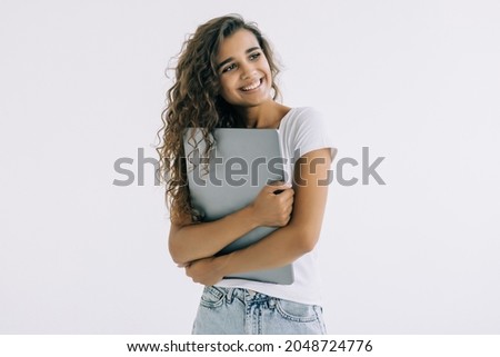 Young woman standing with laptop on white background.