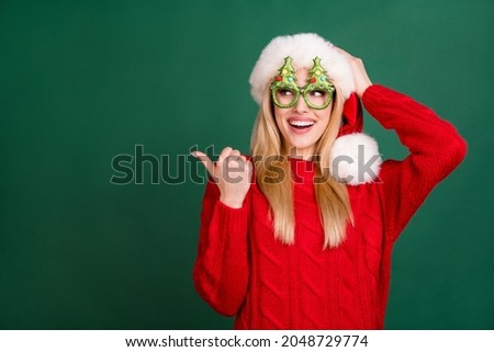 Photo of amazed happy young blonde woman look point finger empty space xmas isolated on green color background