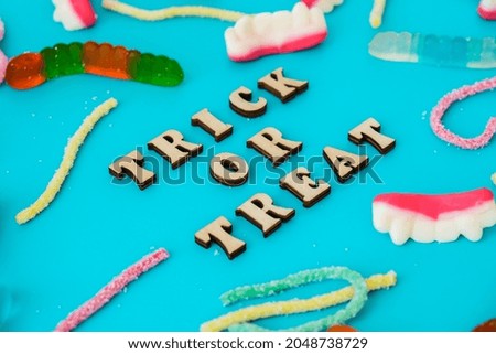 Halloween concept. Halloween party decorations with words TRICK OR TREAT, sweets, top view flat lay on blue background. Greeting card