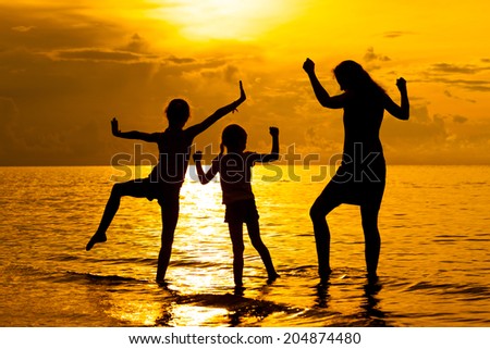 Happy family playing at the beach at the dawn time