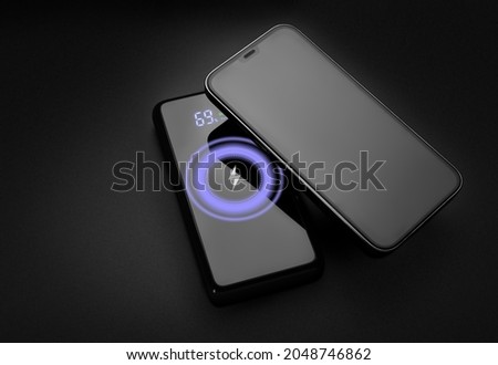 Wireless charging. Wireless power bank charging phone on black background. Modern technology.