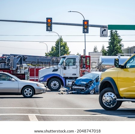 Damaged cars after a car accident crash involving a big rig semi truck with semi trailer at a city street crossroad intersection with traffic light and rescue services to help the injured Royalty-Free Stock Photo #2048747018