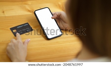 A pretty young lady enters her credit card details into an internet banking application. smartphone blank screen mockup