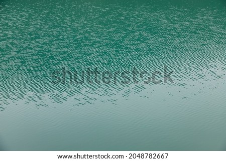 Close up of the turquoise water of a lake. Waves created by the wind
